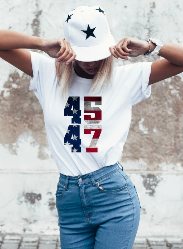 Person wearing a white t-shirt with numbers and a cap, standing against a textured wall. Trump 45/47 America Softstyle Graphic T-Shirt