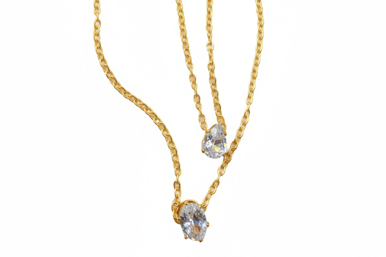 Two gold necklaces with teardrop-shaped gemstones on a white background