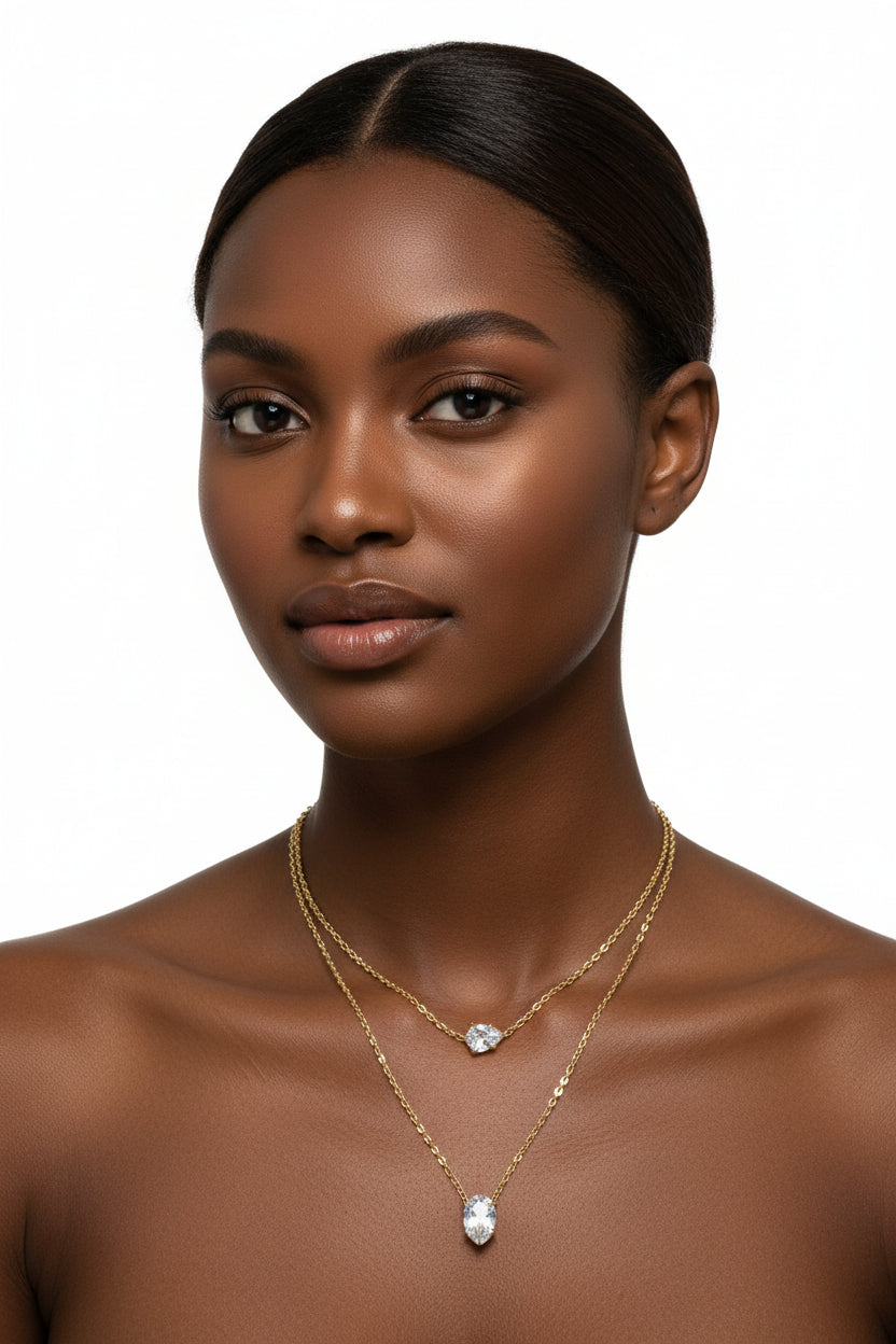 Two gold necklaces with teardrop-shaped gemstones on a white background