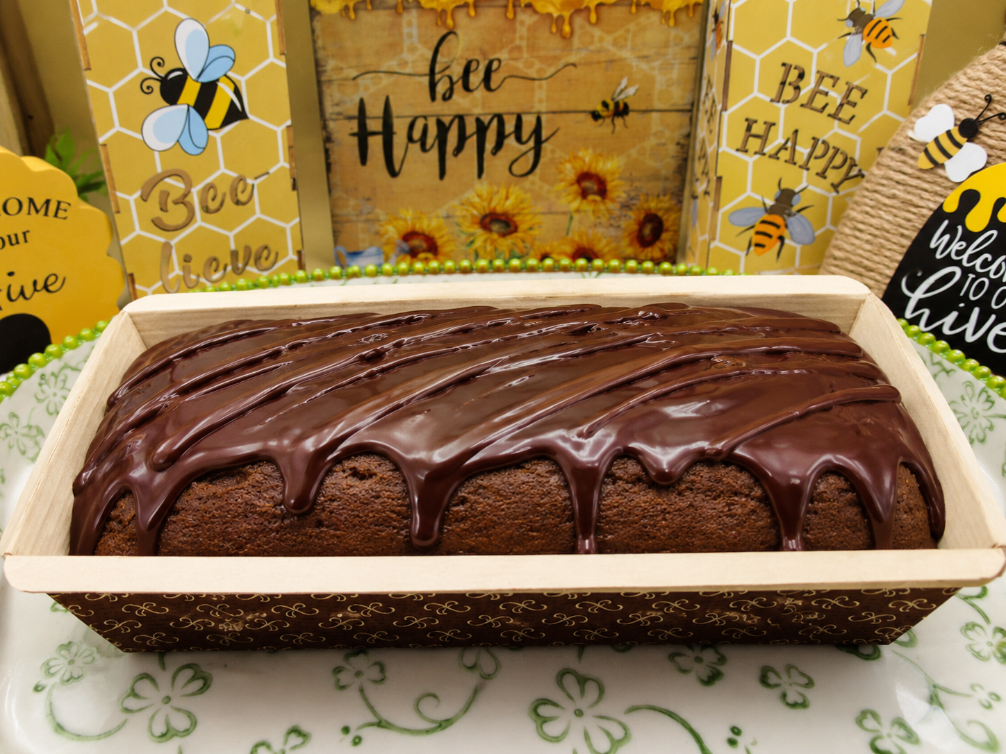 Chocolate cake in a wooden box with 'bee happy' sign in the background