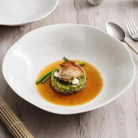 Delicate dish with meat and green vegetables on a white plate with a light background