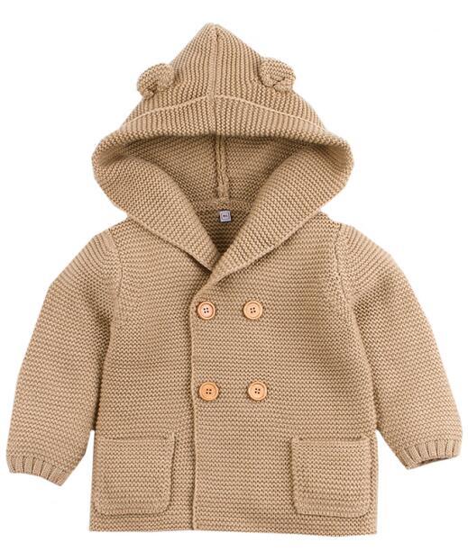 Beige knitted baby coat with hood on a white background