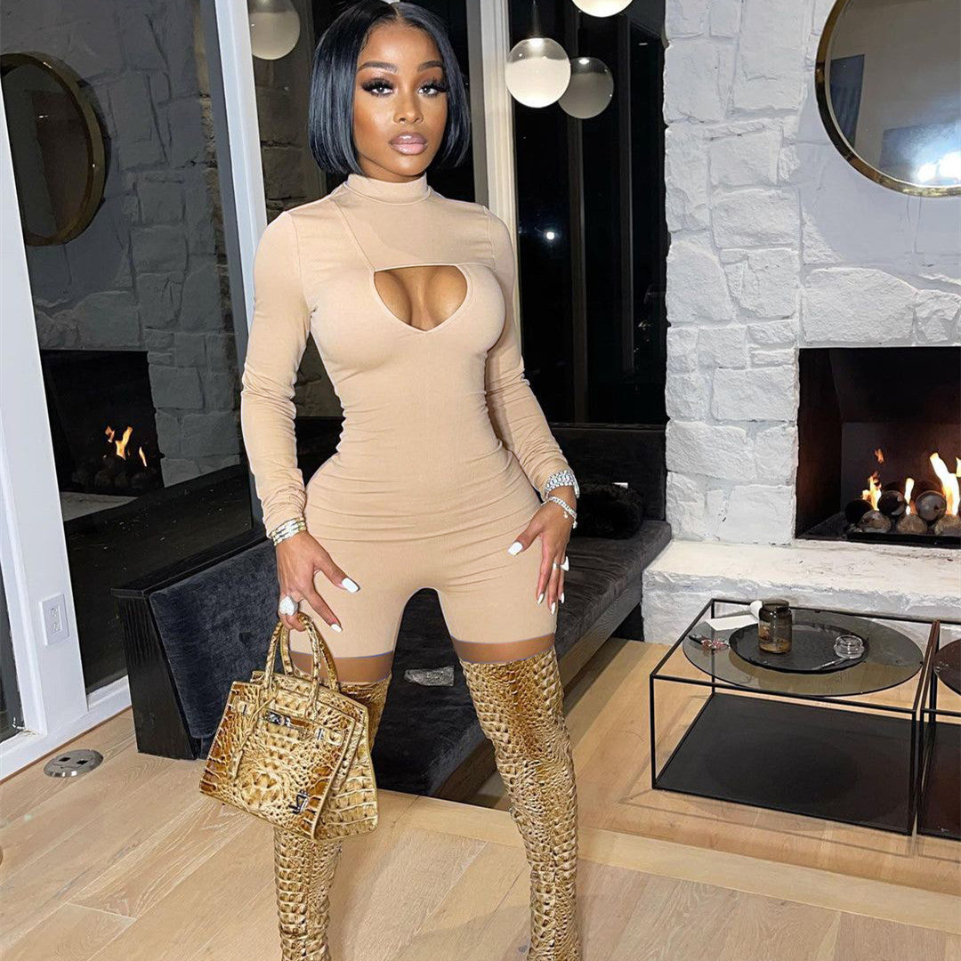 Woman in a beige outfit with cut-out design standing in a stylish room with fireplaces.