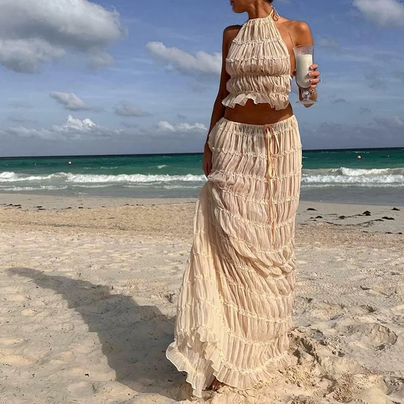 Woman in a long, flowing dress standing on a beach with ocean and sky in the background Woman_in_a_long_tan beige cream flowing_dress_standing_on_a_beach_with_ocean_and_sky_in_the_background_2_piece_set_nice_crinckle_runched_up_bunchedskirt_and_top