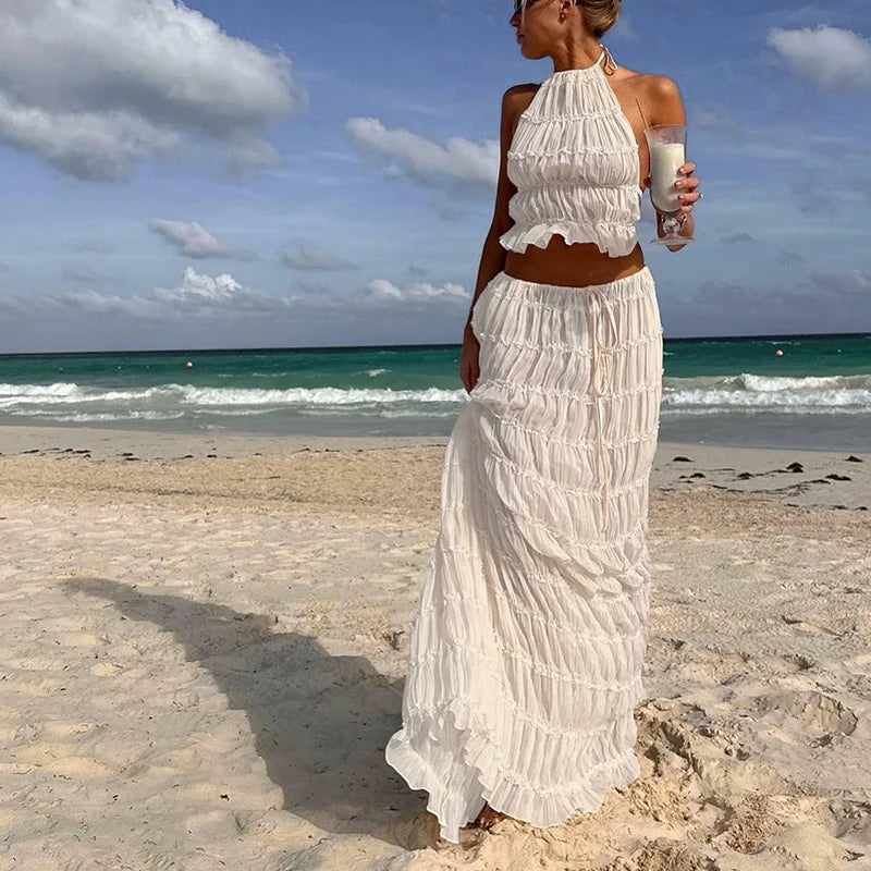 Woman in a white dress standing on a beach with ocean and sky in the background