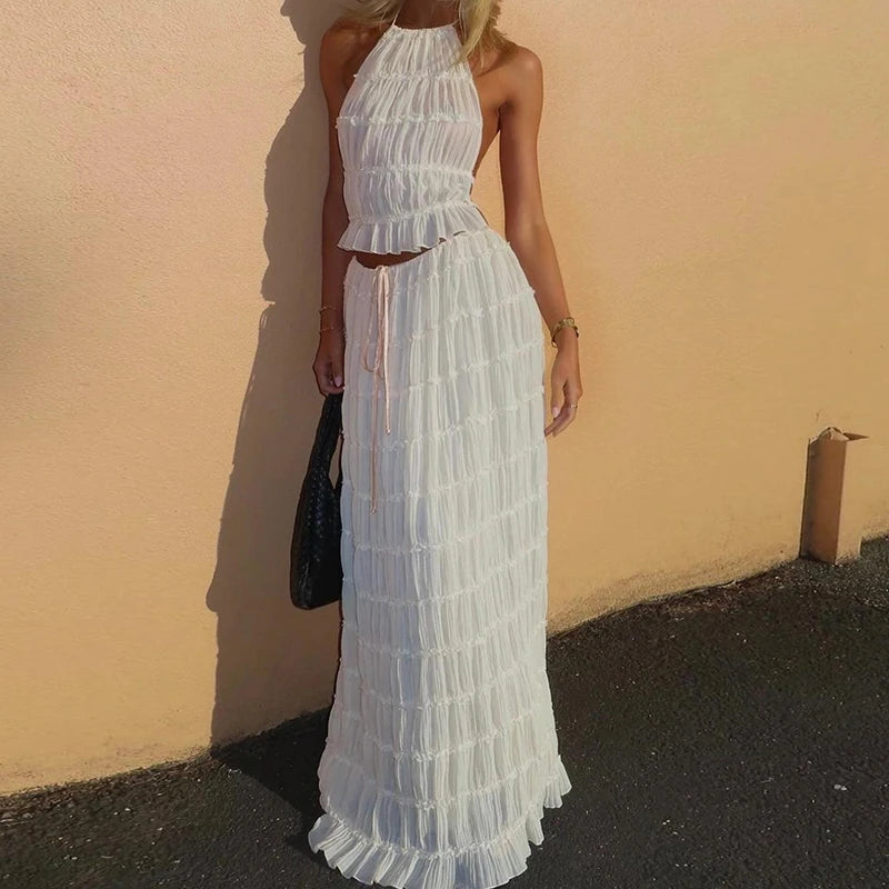 Woman wearing a white lace dress against a beige wall.