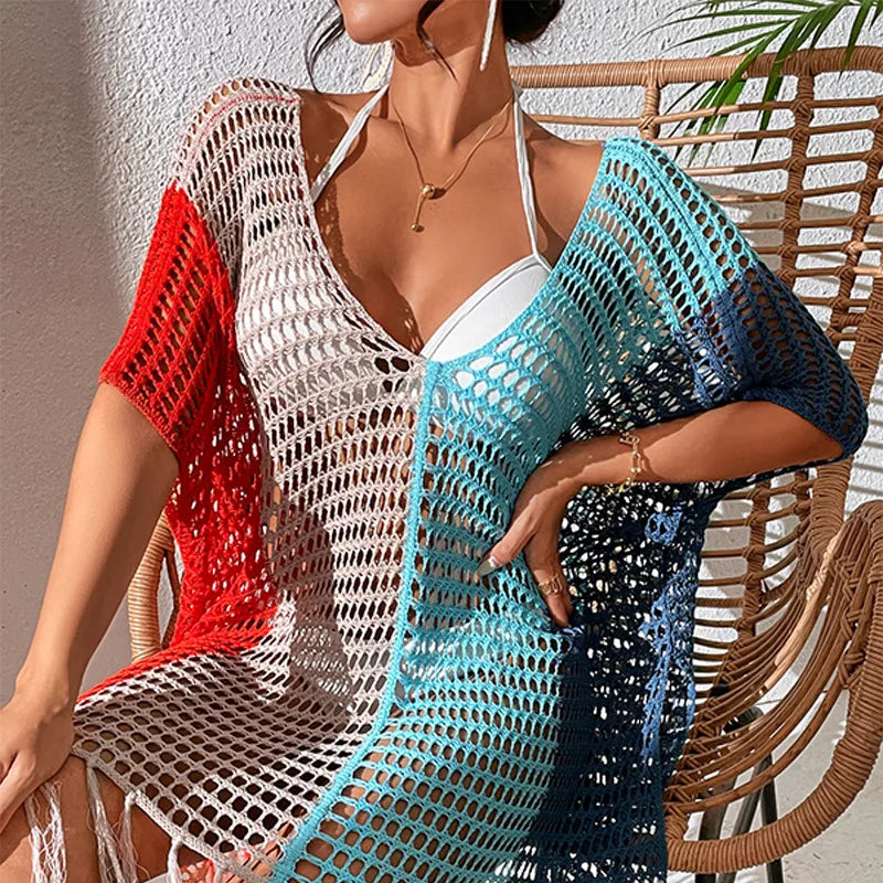 Woman wearing a colorful crochet cover-up sitting on a wicker chair.