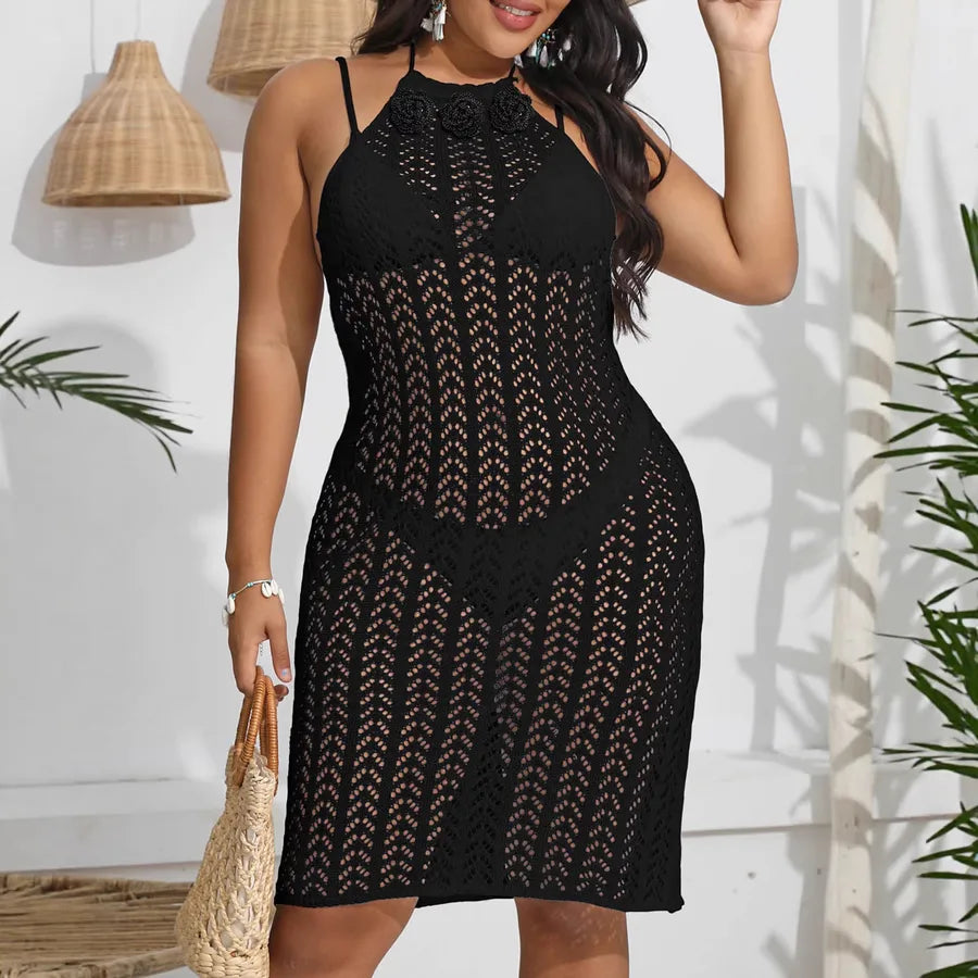 Woman wearing a black lace dress against a white wall with plants.