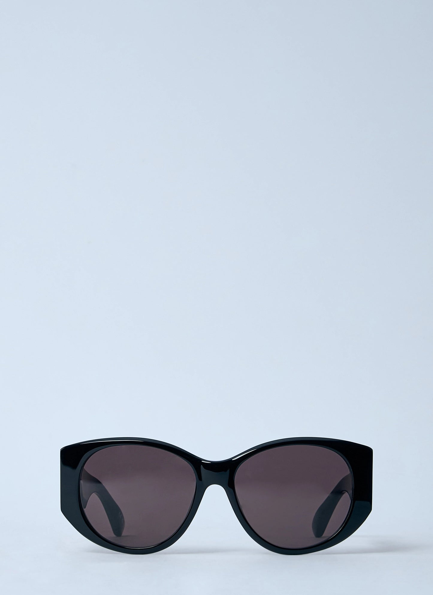 Black sunglasses with dark lenses on a light blue background