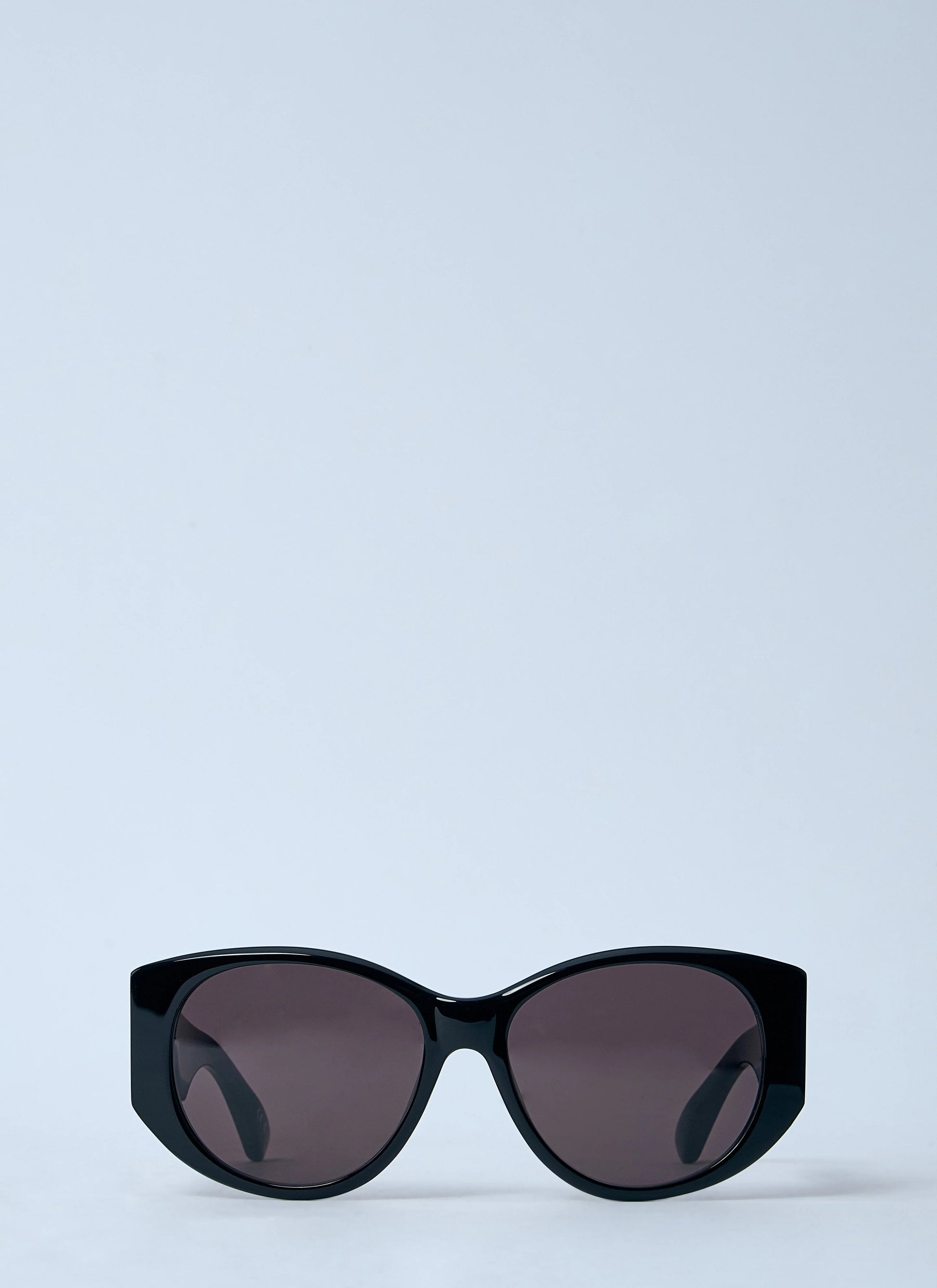 Black sunglasses with dark lenses on a light blue background