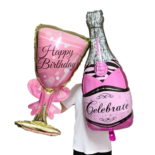 Pink and gold 'Happy Birthday' balloon and pink and silver 'Celebrate' bottle balloon against a curtain background.