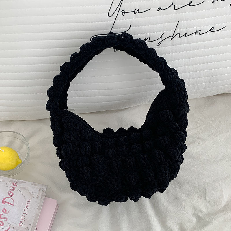 Black knitted headband on a white surface with a blurred background
