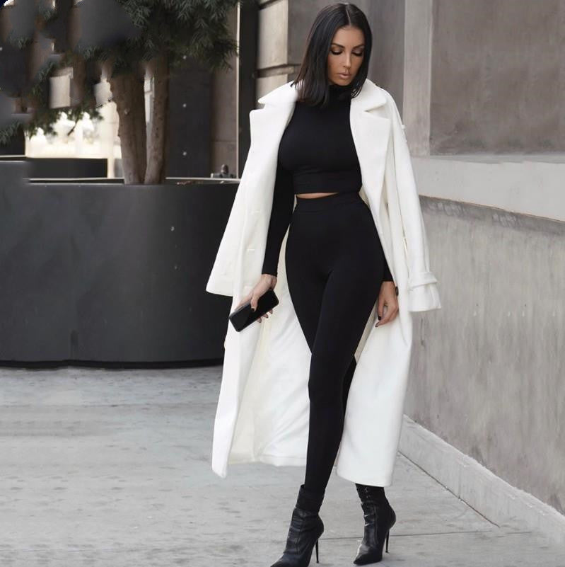 Woman in a white coat and black outfit walking on a city street. Kim Kardashian SKIMS look woman in a black outfit walking on a sidewalk.
