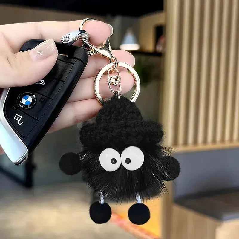 Black fluffy keychain with googly eyes attached to a car key fob.