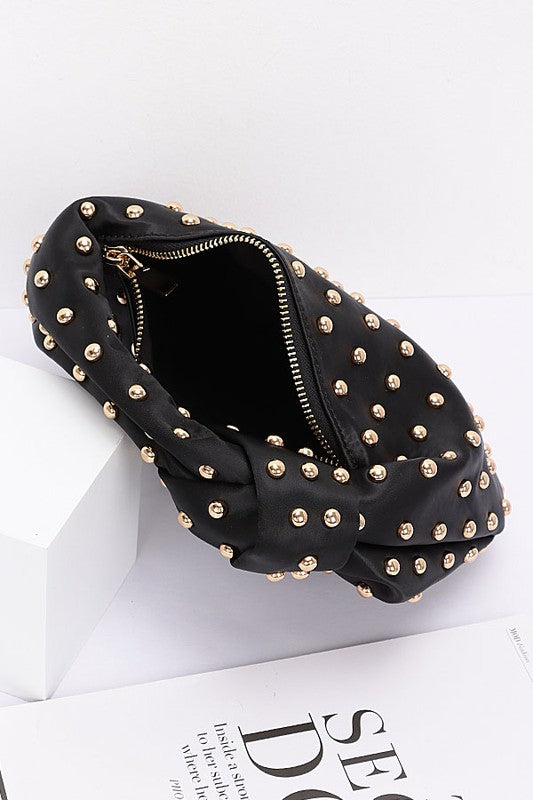 Elevate your evening look with this stunning studded clutch—the perfect blend of sophistication and sass. Featuring a chic knotted handle and soft satin construction, this compact purse slides effortlessly into your night out. The mixed metal studs add just the right amount of edge, while the polyurethane backing ensures durability. At 10" wide and 7" tall, it's sized just right for essentials. Lead and nickel compliant for worry-free style. Your new go-to accessory for turning heads.