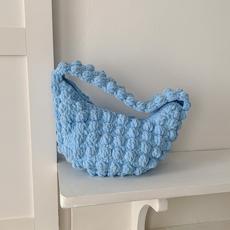 Blue textured bag on a white surface with a light gray wall background