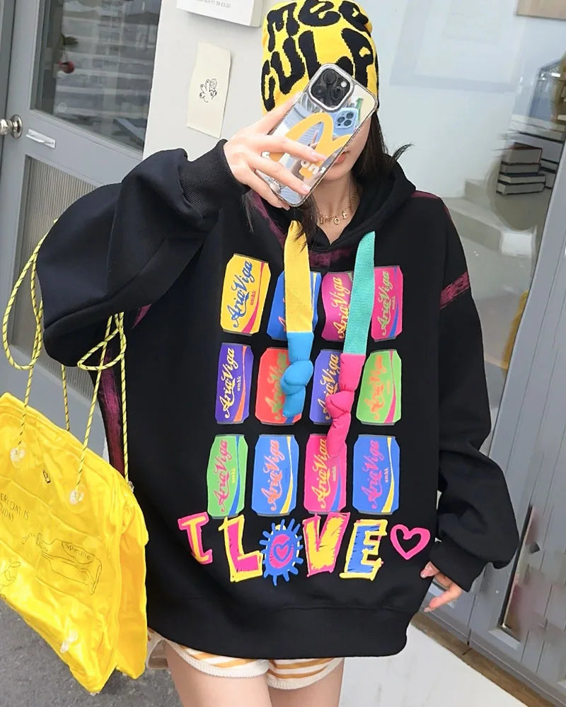Person wearing a black hoodie with colorful text and graphics, holding a yellow bag.