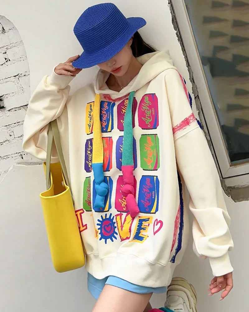 Person wearing a colorful hoodie with text and graphics, holding a yellow bag.