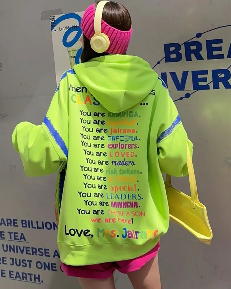 Person wearing a bright green hoodie with text, standing in front of a branded backdrop.