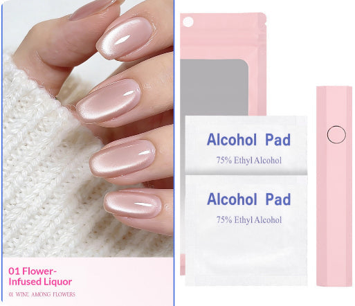 A manicured hand wearing a glossy pale pink nail polish, shown beside product packaging for a nail color set. The packaging includes two white packets labeled 'Alcohol Pad 75% Ethyl Alcohol' and a pink cylindrical item, with a pink label reading '01 Flower-Infused Liquor'.