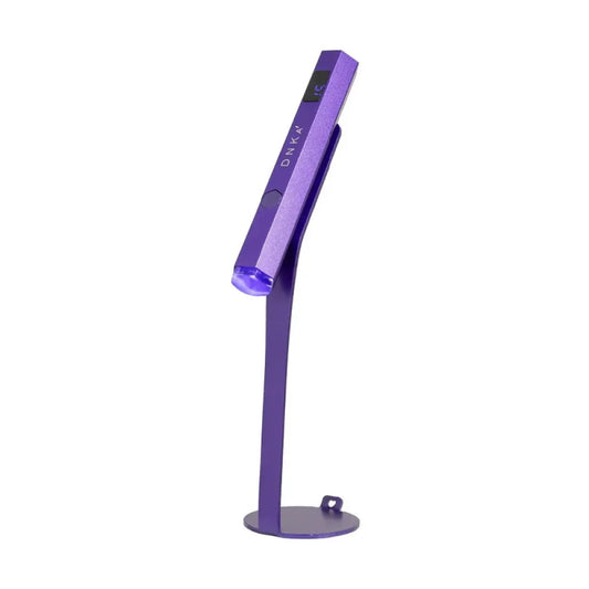Compact, rechargeable DNKa Lumos Light UV/LED flashlight in purple, shown mounted on its magnetic stand against a clean white background.