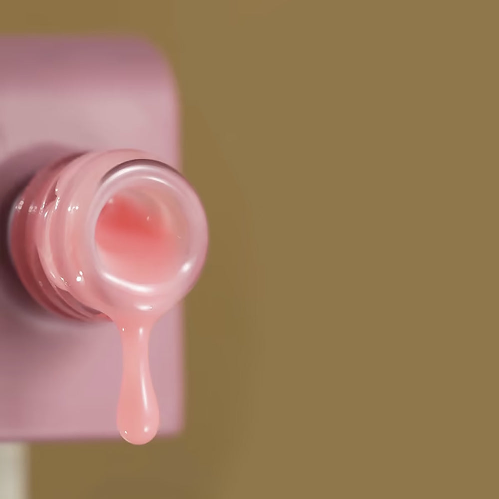 Glossy coral pink gel dripping from an open jar against a solid warm beige background, product photography style.