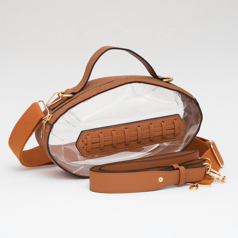 A clear oval shoulder bag with a brown faux-leather top handle, brown strap, and a brown stitched patch detail on the front, shown on a clean white background.