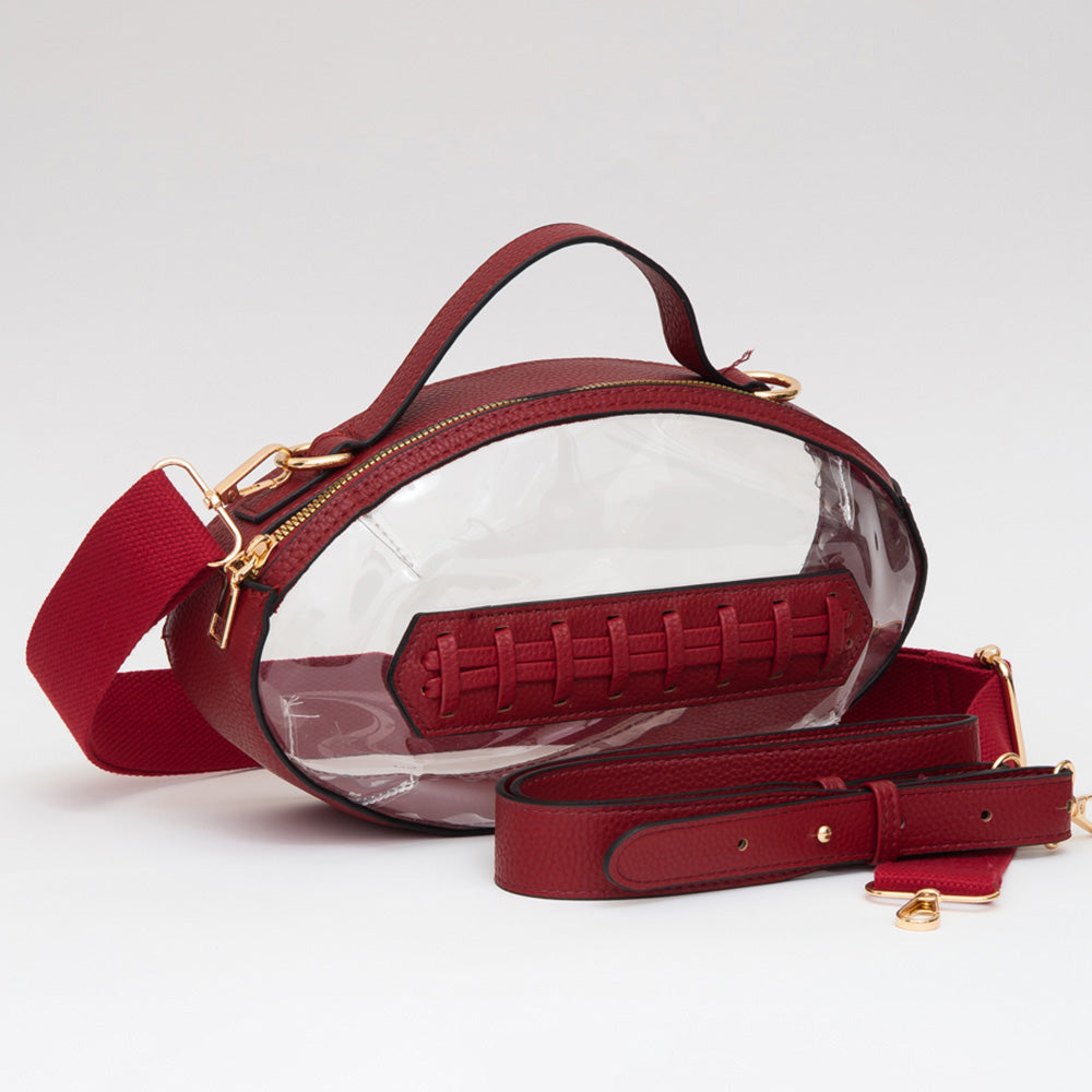 A clear oval handbag with red leather trim, a red top handle, a red shoulder strap, and a faux-stitch detail on the front, photographed on a clean white studio background.