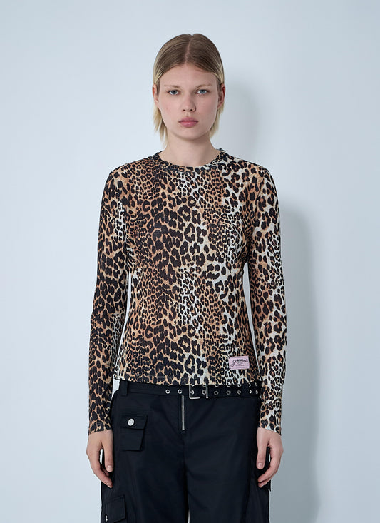 Model wearing a Ganni long-sleeve mesh top featuring a brown leopard print pattern and a branded logo patch on the chest, showcased against a clean, light gray background.