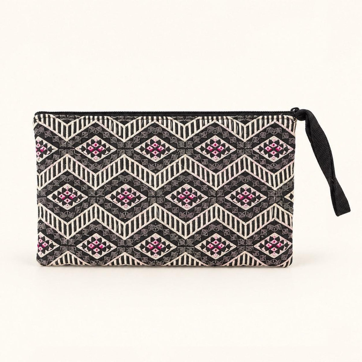 A rectangular clutch pouch with a geometric pattern in black, beige, and pink, featuring a black zipper and a black wrist strap, set against a plain off-white background.