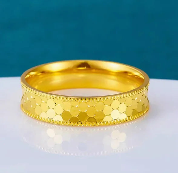 24k Gold ring on a white surface with a blue background