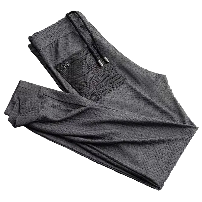 Folded gray pants with a brand logo on a dark background