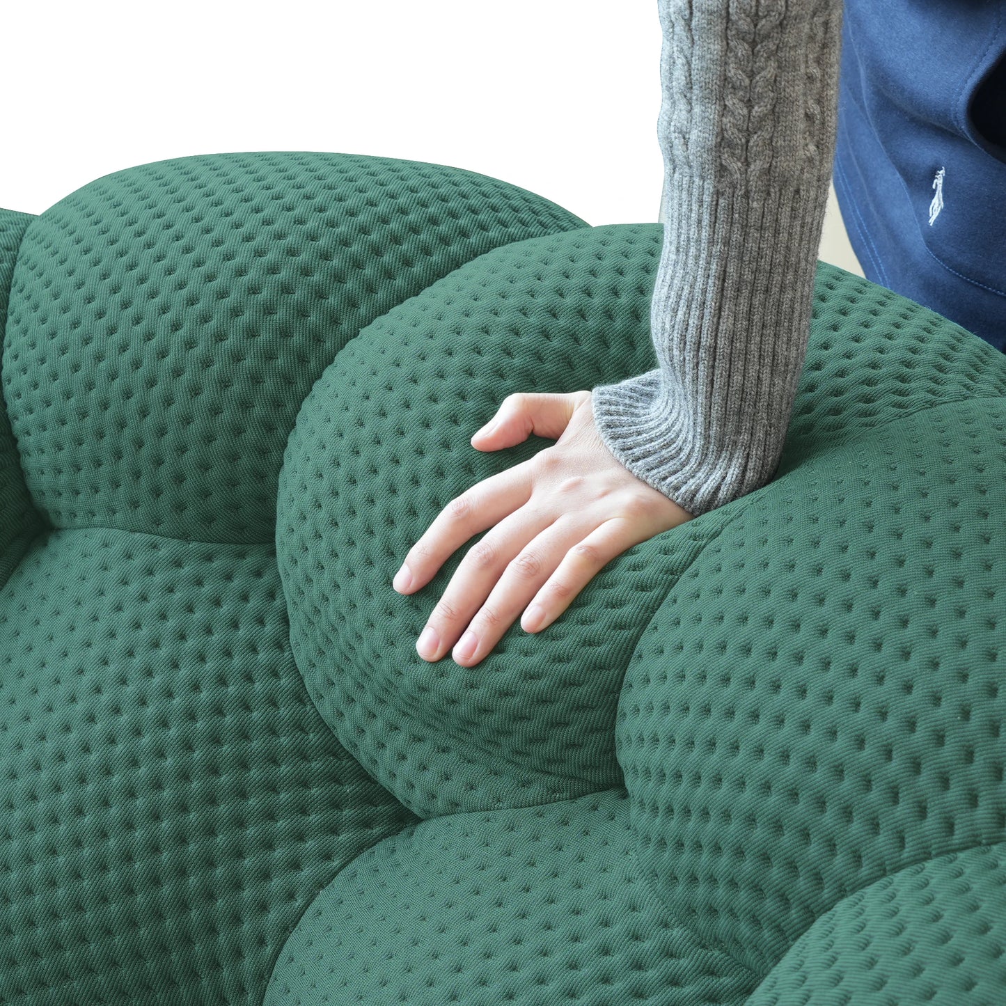 Person sitting on a green textured sofa with one hand resting on the armrest.