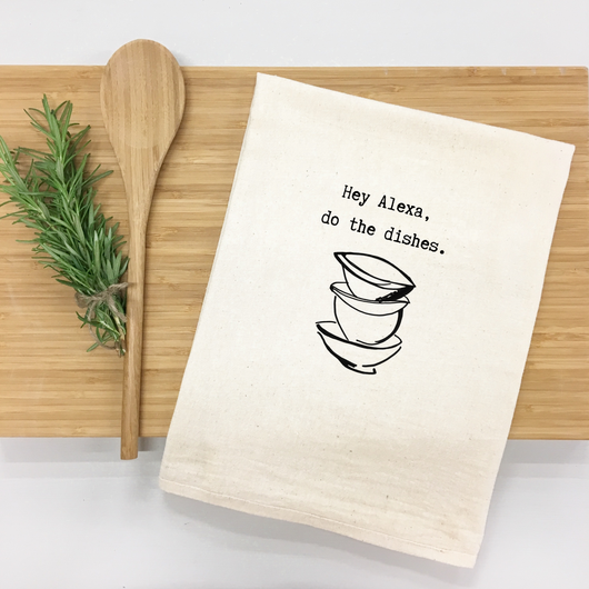 Kitchen towel with 'Hey Alexa, do the dishes' text and bowl graphic on a wooden cutting board with a spoon and rosemary.