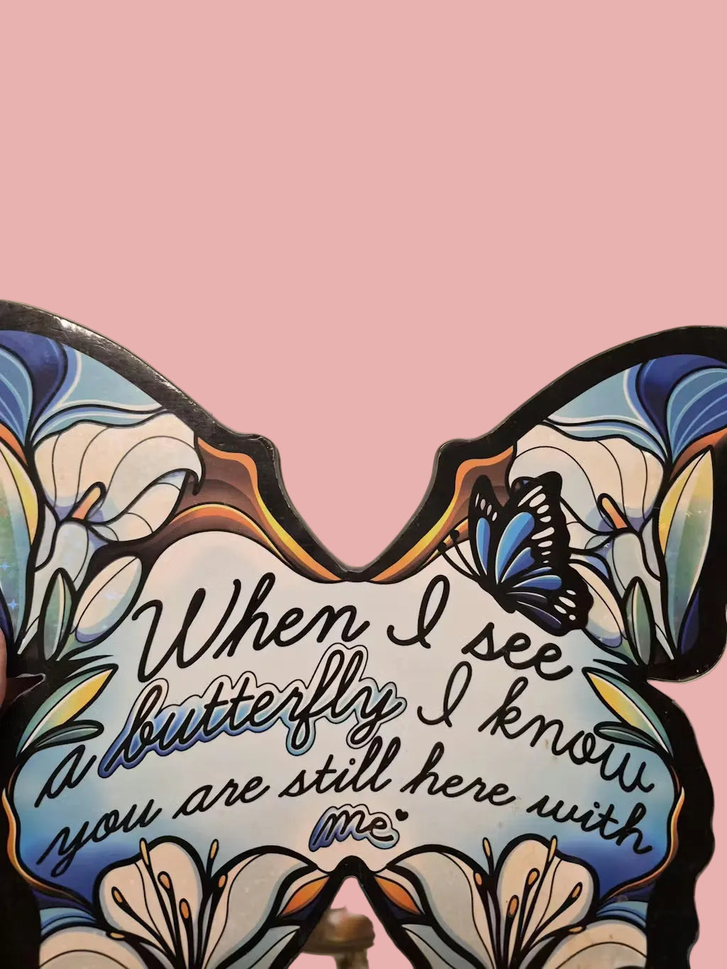 Decorative butterfly-shaped sign with floral designs and text on a beige background