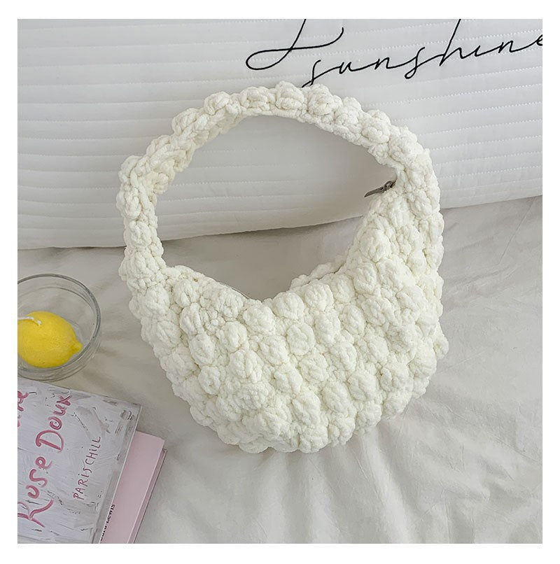 White textured handbag on a light surface with 'sunshine' text in the background