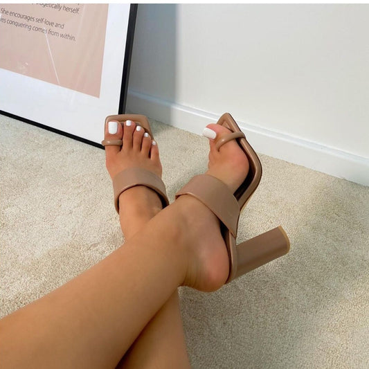 light brown Beige high-heeled sandals worn on a carpeted floor.