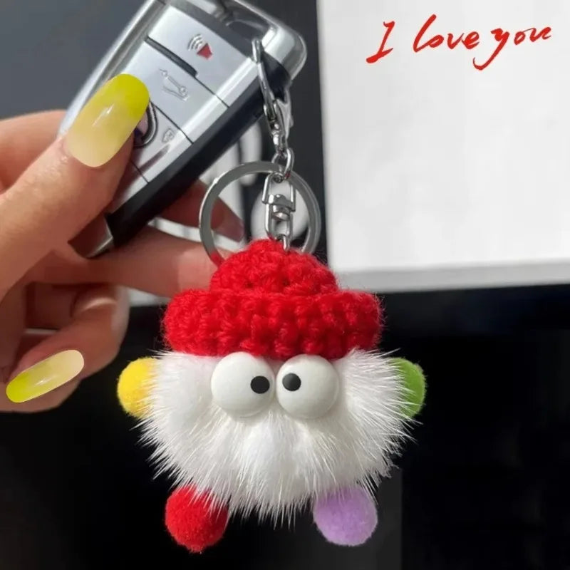 Keychain with a fluffy character wearing a red hat held by a hand, with 'I love you' text in the corner.
