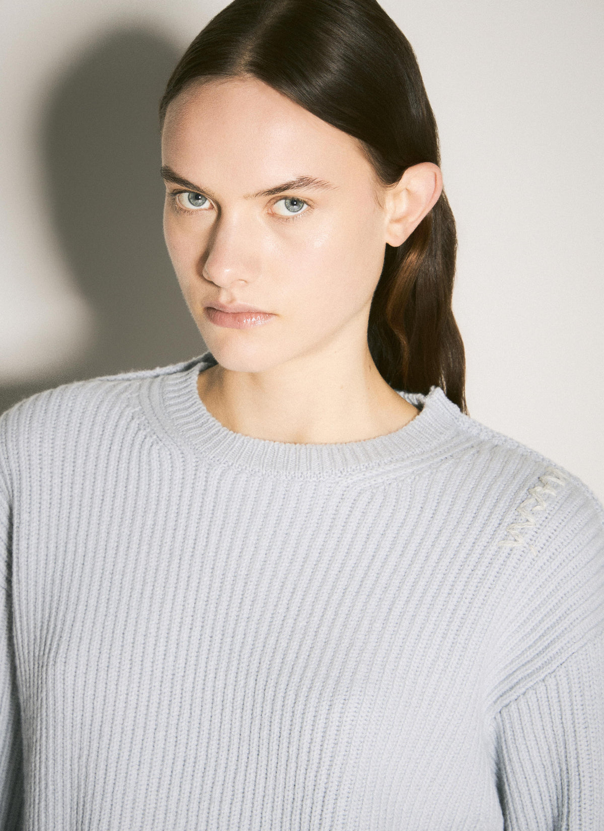 A light gray Marni crewneck wool sweater modeled against a plain, neutral background, showcasing the knit texture and long sleeves.