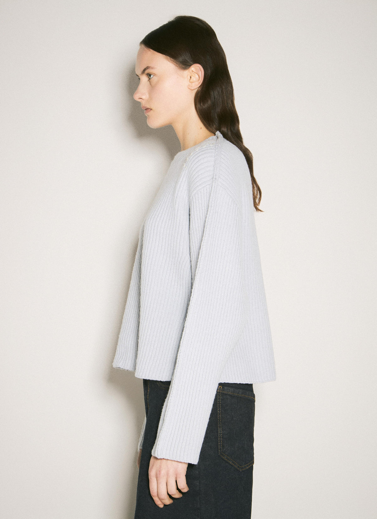 Marni women's gray ribbed wool crewneck sweater worn by a woman in profile, paired with dark jeans against a neutral off-white background.