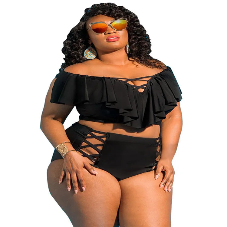 Woman wearing a black off-shoulder top and high-waisted bikini bottom with sunglasses on a white background