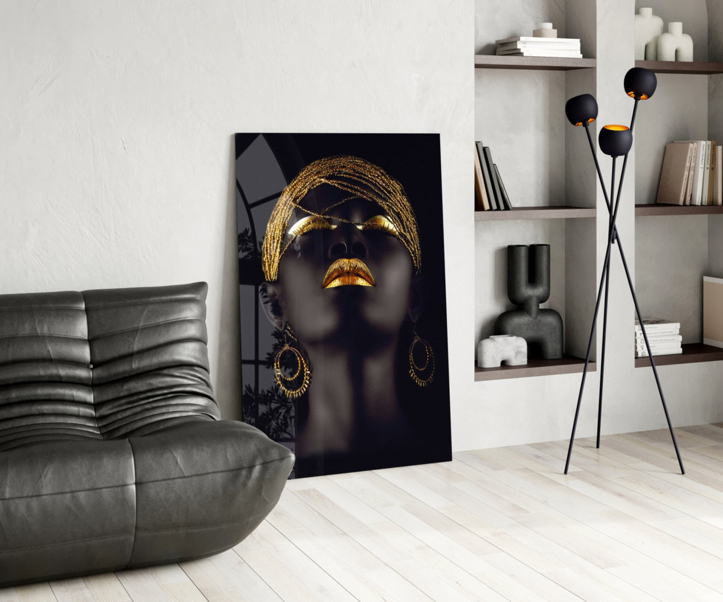 Modern interior with a black and gold art piece on the wall, gray sofa, and decorative shelves. Gold Beaded Headdress Woman Glass Wall Art