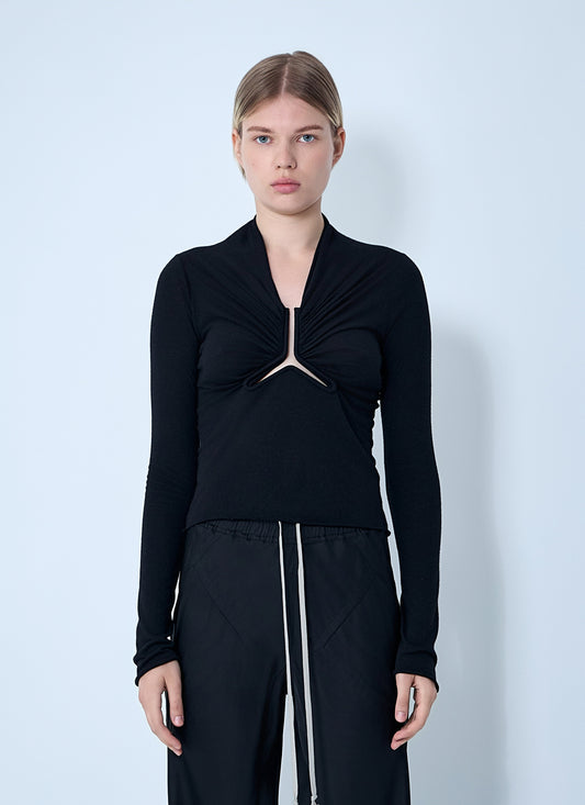 Model wearing a black Rick Owens Allanah long-sleeve top featuring a V-neck and unique front cut-out construction against a minimalist light blue background.