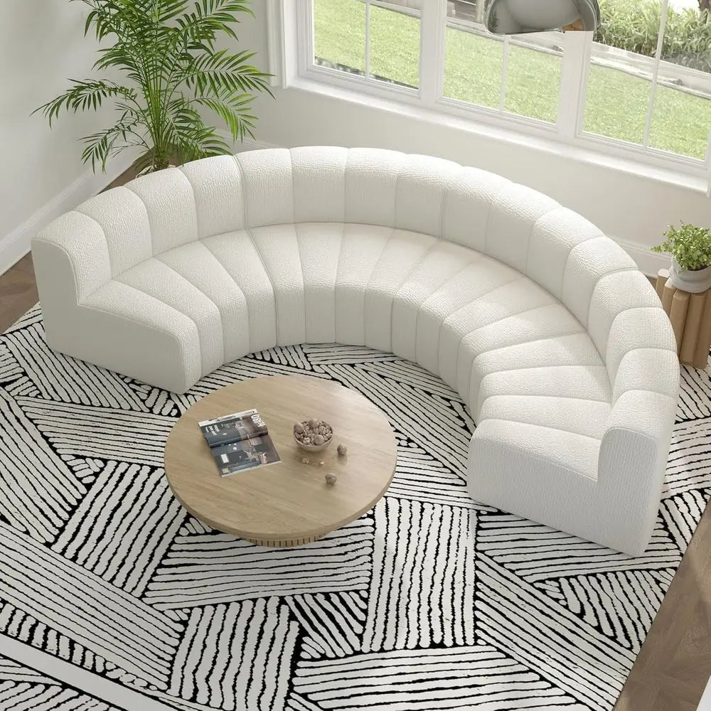 White curved sectional sofa in a room with a patterned rug and a coffee table.