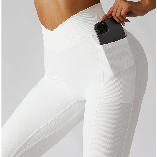Person wearing white leggings with a pocket holding a phone on a light gray background
