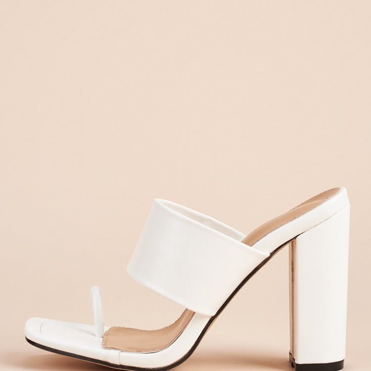 White high-heeled shoe on a beige background
