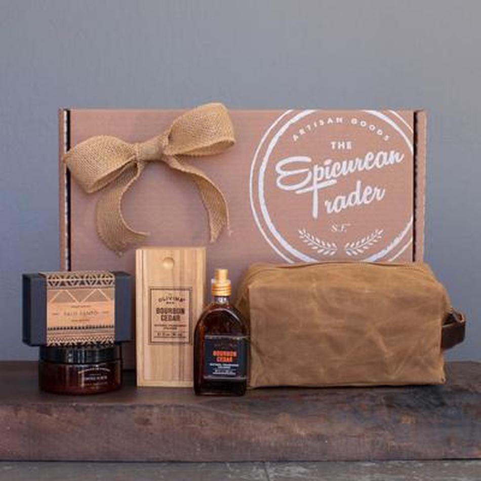 Gift set with a bottle, box, and pouch on a wooden surface with a branded box in the background.